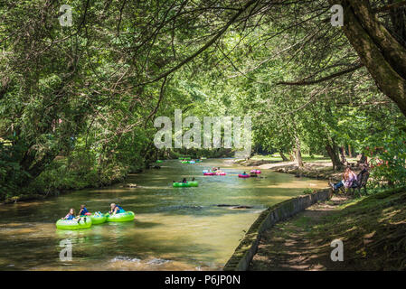 Die Menschen genießen einen entspannenden Sommertag unter einer überdachung der Bäume am Chattahoochee River in Helen, Georgia. (USA) Stockfoto