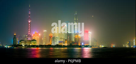 Chinesische Skyline von Shanghai glühende in einer nebligen Nacht, worin sich im Wasser des Flusses Huangpu - Vollmond im Hintergrund Stockfoto