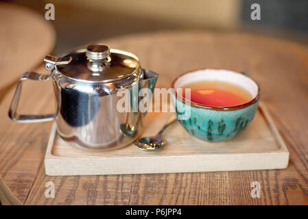 Stillleben mit Tasse Tee, Teekanne und Schale auf einem Holztisch im Cafe innen gesetzt. Stockfoto