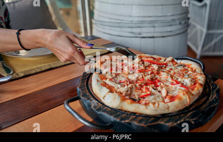 Mädchen nimmt ein Stück Pizza aus der Tabelle Stockfoto