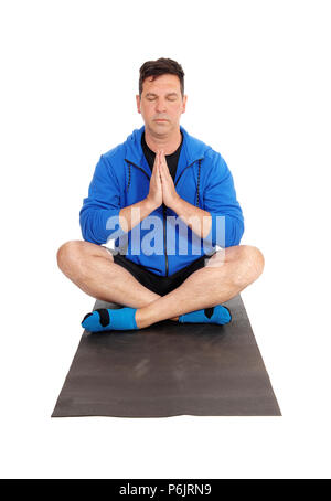 Eine meditierende Mann in einer blauen Jacke auf dem Boden sitzend in einer Yoga pose mit geschlossenen Augen und Hand gefaltet, auf weißem Hintergrund Stockfoto