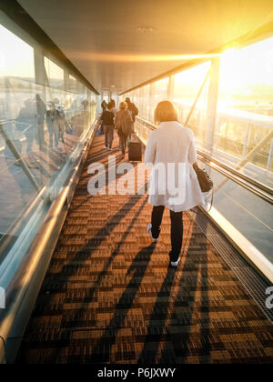 Frau hinunter Airport finger Flugzeug mit dem Sonnenlicht durch die Fenster scheint. Stockfoto