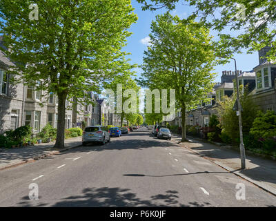 Der schattigen Gehwegen einer Aberdeen City mit Bäumen gesäumten Straße, mit parkenden Autos außerhalb Bewohner Häuser auf einem Morgen Sommern. Aberdeen, Schottland. Stockfoto