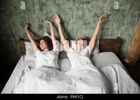 Glückliches junges paar Stretching im Bett nach dem Aufwachen Stockfoto