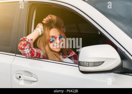 Glückliche junge Frau mit Sonnenbrille im Auto mit ihrem Mann glücklich ist Stockfoto