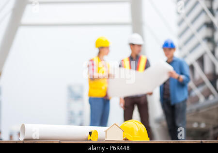 Haus, Zuhause, Papier Plan oder Entwurf und andere Ingenieur Werkzeuge mit Hintergrund der Erfolg Ingenieur Team über die Arbeit in der Business Zone diskutieren Stockfoto