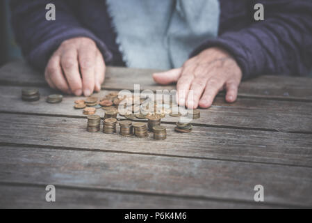 Geld, Münzen, die Großmutter auf das Renten- und das Konzept des Lebens, Minimum - faltige Hand der alten Frau touch Münzen auf einen hölzernen Tisch Stockfoto