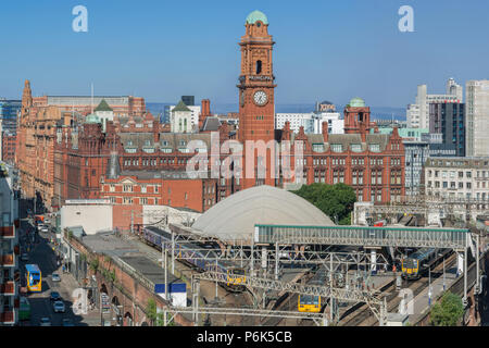 Züge eingeben und Abfahrt Bahnhof Oxford Road in Manchester mit dem Principal Hotel hinter steigt. Stockfoto