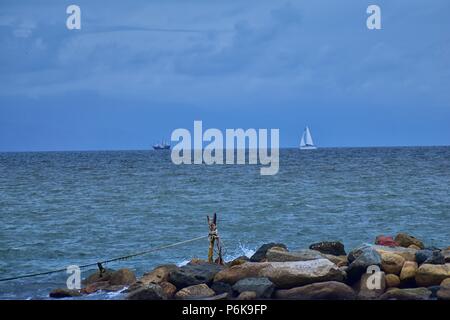 Piratenschiff und Segel Yacht aus der Entfernung mit Felsen im Vordergrund von Strand in Puerto Vallarta, Mexiko. Stockfoto