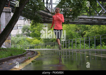 Runner Frau im Park im Regen laufen Stockfoto