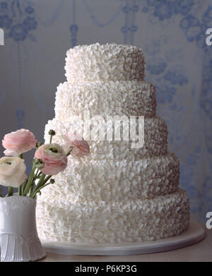In der Nähe von fünf Tier weiß iced Hochzeitstorte und rosa Ranunkeln in weiße Vase Stockfoto