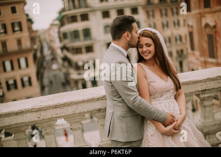 Junge attraktive neu verheirateten Paar und in Rom posiert mit schönen und antike Architektur auf dem Hintergrund am Tag ihrer Hochzeit Stockfoto