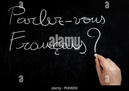 Sprechen Sie Französisch Frage handschriftlich auf dem schwarzen Brett von männlichen Hand mit weißer Kreide Stockfoto