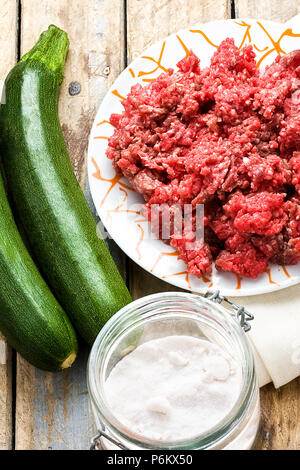 Rohes Hackfleisch zwei Zucchini und Salz auf hölzernen rustikalen Tisch Stockfoto