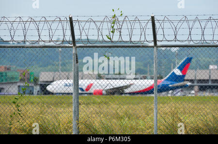 Phuket, Thailand - 23.April 2018. Zaun mit Stacheldraht um Flughafen mit einer Dockingstation Flugzeug in Phuket International Airport (HKT). Stockfoto