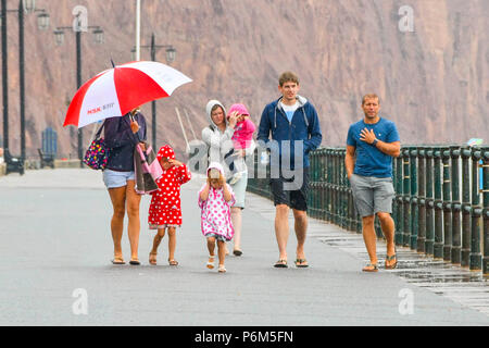 Honiton, Devon, Großbritannien. 1. Juli 2018. UK Wetter. Besucher in den Badeort Sidmouth Devon mit einem Regenschirm, der als die Stadt fängt den Rand eines vorbeifahrenden heftiger Regenschauer. Foto: Graham Jagd-/Alamy leben Nachrichten Stockfoto