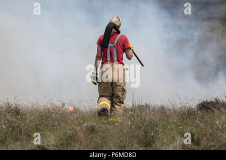 Lancashire, UK. 1. Juli 2018 - Weibliche Feuerwehrleute versuchen, den wachsenden moorland Feuer auf Winter Hill und Rivington Pike, die eine Anzahl von Tagen gestartet wurde. Feuer Besatzungen aus über Großbritannien haben im Winter Hill konvergierten die Flamme, die Meter pro Stunde wachsen zu steuern. Lancashire Feuer und Rettung und Lancashire Polizei führen die Antwort auf die 'Major Incident'. Credit: Benjamin Wareing/Alamy leben Nachrichten Stockfoto