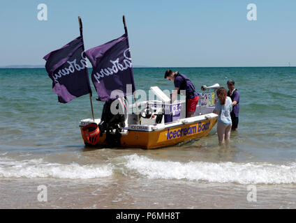 Ein Eis Boot verkauft Eis an Touristen in sehr warmem Wetter 25. Juni 2018 in der Brandung am Strand von Sandbänken, Poole, Dorset, England, Großbritannien Stockfoto