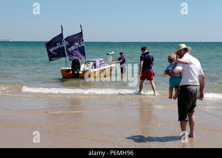 Ein Eis Boot verkauft Eis an Touristen in sehr warmem Wetter 25. Juni 2018 in der Brandung am Strand von Sandbänken, Poole, Dorset, England, Großbritannien Stockfoto