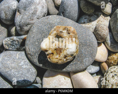 Am Strand, ein Stein in der Form eines menschlichen Gesichts. Stockfoto