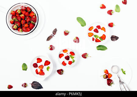Portionen Erdbeereis auf einem weißen Tisch, Ansicht von oben. Flach Anordnung der Vorbereitung im Sommer kalt erfrischende Desserts mit Rot gehalten werden. Stockfoto