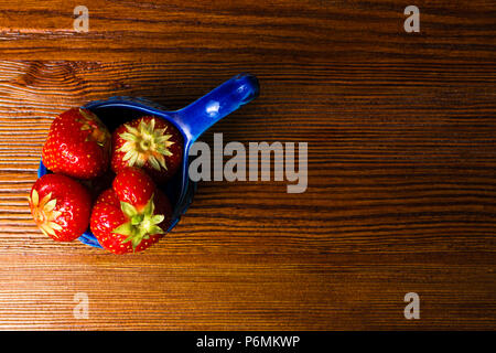 Frische Erdbeeren in blauer Schüssel auf alten hölzernen vintage Tabelle. Rot saftige Erdbeere Stockfoto