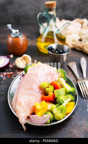 Rohes Hähnchenfilet mit frischem Gemüse auf dem Teller Stockfoto