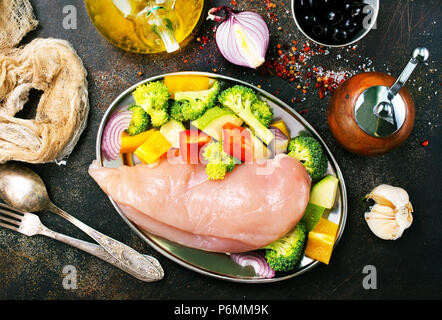 Rohes Hähnchenfilet mit frischem Gemüse auf dem Teller Stockfoto