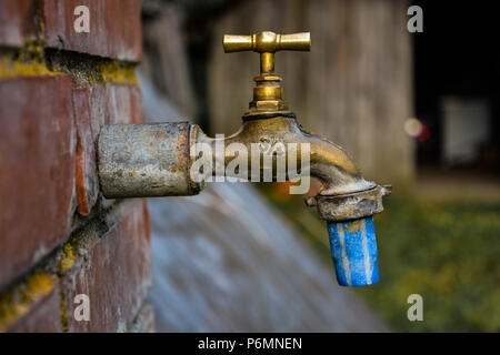 Alten und gebrauchten Vintage Wasserhahn isoliert. Profil von Bronze Metallic Wasserhahn, mit blauen Ein weißes Rohr am Ende und Anzahl 3/4 auf der einen Seite und DF auf anderen. Stockfoto