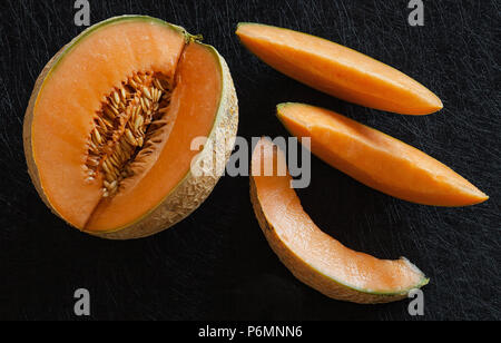 Reife Melone in Scheiben geschnitten auf schwarzem Hintergrund, dunklen Stil essen von oben gesehen. Stockfoto