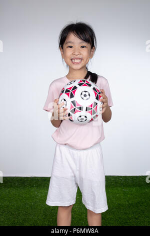 Asiatische kleinen chinesischen Mädchen, dass Fußball im Fußball Feld Stockfoto