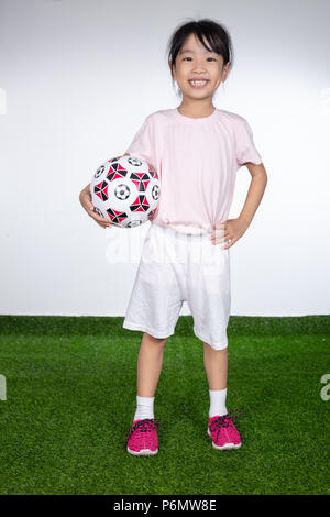 Asiatische kleinen chinesischen Mädchen, dass Fußball im Fußball Feld Stockfoto