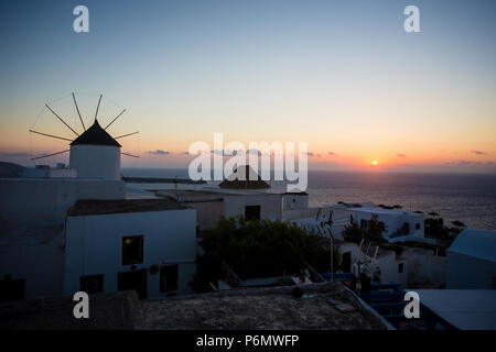 Mykonos, Griechenland. Sonnenuntergang über dem Meer mit berühmten Windmühlen der Griechischen Insel Mikonos, von der Terrasse aus gesehen. Die Kykladen Stockfoto