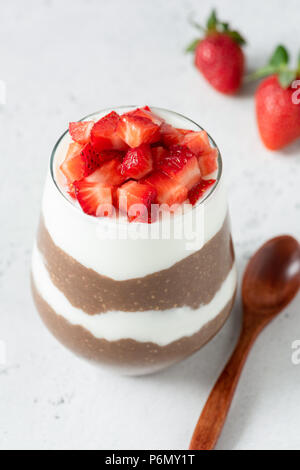 Chia Pudding mit Schoko und Erdbeeren im Glas auf grauem Beton Hintergrund. Gesunde Lebensweise, gesunde Ernährung Konzept Stockfoto