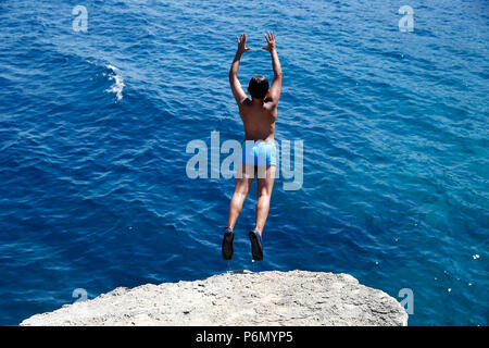 11-jähriger Junge von einem Felsen ins Meer im Salento, Italien springen. Stockfoto