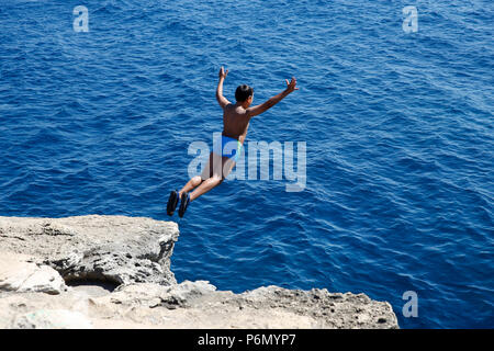 11-jähriger Junge von einem Felsen ins Meer im Salento, Italien springen. Stockfoto