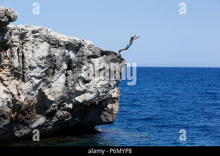 11-jähriger Junge von einem Felsen ins Meer im Salento, Italien springen. Stockfoto