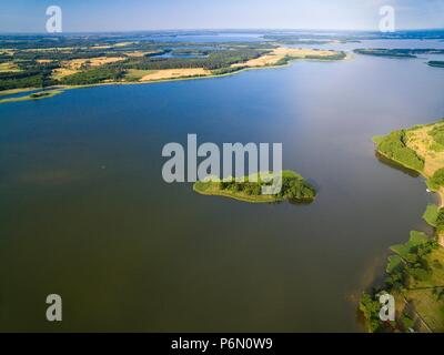 Luftaufnahme der kleine unbewohnte Insel auf dem See mit Sky in ruhigem Wasser reflektiert, Swiecajty See, Masuren, Polen Stockfoto