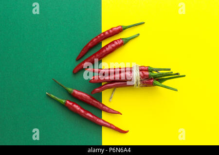 Ansicht von oben, viele rote Chilischoten auf einem gelb-grünen Hintergrund Stockfoto