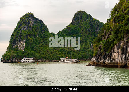 Tour Boote auf Halong Bay navigieren Vergangenheit große Felsformationen. Stockfoto