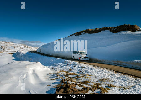 Ein Mazda Bongo campervan vorbei an einem großen Snow Drift in der Nähe der Gipfel des Bealach Na Bà Strasse, die in den Applecross Hills, Hochland, Schottland, Großbritannien Stockfoto