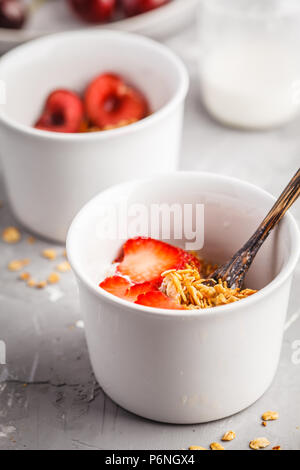 Hausgemachtes Müsli mit Joghurt und Beeren in kleinen weißen Schalen. Gesunde Ernährung Konzept. Stockfoto
