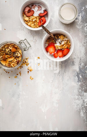 Hausgemachtes Müsli mit Joghurt und Beeren in kleinen weißen Schalen, Ansicht von oben, kopieren. Gesunde Ernährung Konzept. Stockfoto