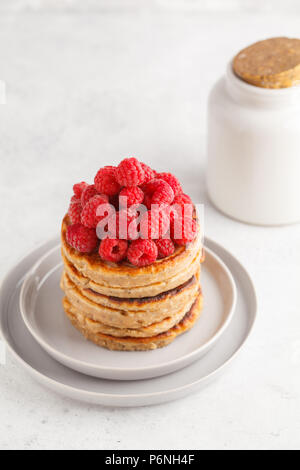 Vegane Pfannkuchen mit Himbeeren und Chia Samen auf eine weiße Platte, weisser Hintergrund. Gesunde vegane Ernährung Konzept. Stockfoto