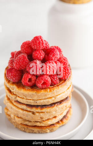 Vegane Pfannkuchen mit Himbeeren und Chia Samen auf eine weiße Platte, weisser Hintergrund. Gesunde vegane Ernährung Konzept. Stockfoto