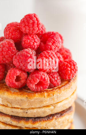 Vegane Pfannkuchen mit Himbeeren und Chia Samen auf eine weiße Platte, weisser Hintergrund. Gesunde vegane Ernährung Konzept. Stockfoto