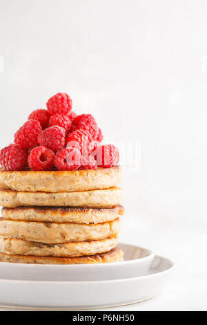 Vegane Pfannkuchen mit Himbeeren und Chia Samen auf eine weiße Platte, weisser Hintergrund. Gesunde vegane Ernährung Konzept. Stockfoto