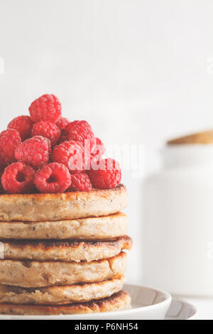 Vegane Pfannkuchen mit Himbeeren und Chia Samen auf eine weiße Platte, weisser Hintergrund. Gesunde vegane Ernährung Konzept. Stockfoto