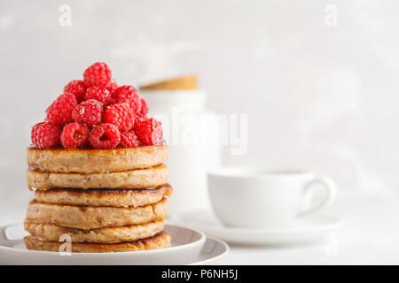 Vegane Pfannkuchen mit Himbeeren und Chia Samen auf eine weiße Platte, weisser Hintergrund. Gesunde vegane Ernährung Konzept. Stockfoto