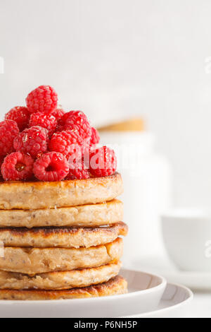 Vegane Pfannkuchen mit Himbeeren und Chia Samen auf eine weiße Platte, weisser Hintergrund. Gesunde vegane Ernährung Konzept. Stockfoto